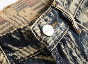 Macro shot of heavy washed denim waist featuring tiger bleach pattern and metal button