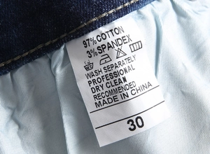 Detail view of denim jeans care label showing 97% cotton and 3% spandex composition