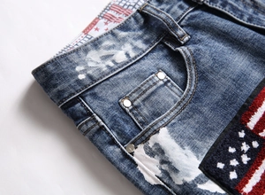 Detailed embroidery patch with star pattern and metal rivets on blue washed denim pants