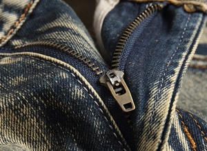 Macro shot of vintage bronze zipper and distressed denim texture on street style shorts