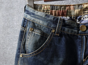 Detailed macro view of vintage distressed denim jeans with bronze buttons and rivets