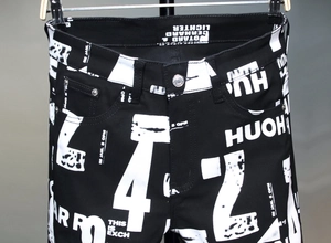 Detailansicht von weißem Graffiti-Druck und Metallknopf auf Herren-Jeans in Schwarz