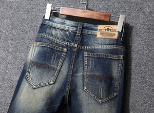 Close-up of deep blue vintage jeans with washed texture and fashion leather patch detail