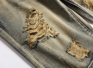 Close-up of vintage yellow washed denim shorts featuring heavy distressed ripped details
