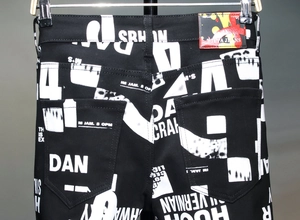 Detailansicht der schwarzen Herrenjeans mit weißem Buchstabendruck und Lederpatch am Taillenbund