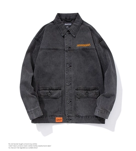 Close-up of the grey denim jacket featuring orange embroidery and flap chest pockets