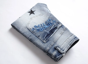 Close-up of heavy embroidery and printed star on blue washed denim jeans back pocket