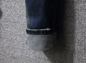 Close-up of deep blue denim jeans featuring folded cuffs and detailed twill texture