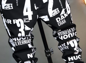 Detail einer schwarzen Streetstyle-Hose mit auffälligen weißen Buchstaben und Zahlen