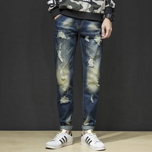 Detail view of distressed ripped denim with heavy whiskers and vintage wash finish