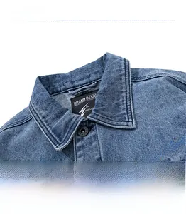 Detail of blue wash denim jacket collar with bright orange letter embroidery