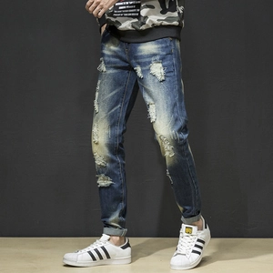 Detail of slim-fit distressed jeans with vintage wash and ripped street style finish