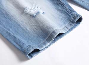Gros plan sur un short en jean bleu clair avec ourlet effiloché et coutures orange