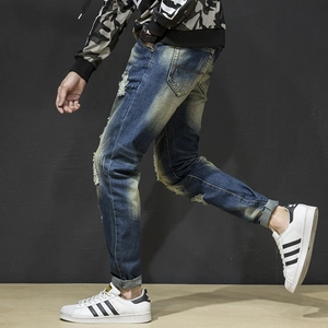 Detail of distressed ripped denim jeans showing vintage wash and slim fit profile