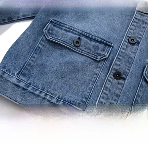 Detail of washed blue denim jacket featuring a cargo pocket and branded black button
