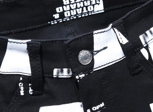 Detail einer schwarzen Jeans im Streetstyle mit Silberknopf und weißen Grafik-Buchstaben