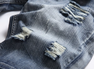 Macro shot of light blue distressed denim shorts with vintage wash and ripped details