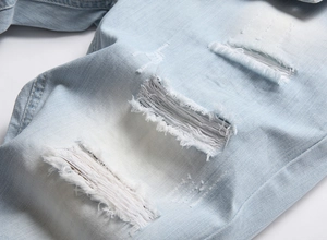 Détail d'un short en jean bleu clair avec des trous effilochés et une texture délavée