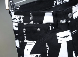 Detailaufnahme der schmalen Herrenjeans mit Streetstyle-Grafikdruck und Metallknopf