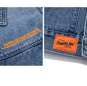 Detailed view of blue heavy denim jacket featuring orange embroidery and woven brand label