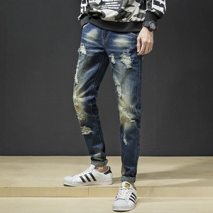 Detail view of men's slim fit distressed blue jeans with ripped knees and vintage wash style