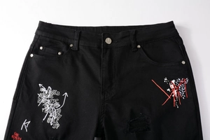 Détail d'un jean noir avec broderie graffiti blanche et accents de lignes rouges