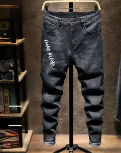 Detail of slim-fit black denim jeans featuring white floral embroidery and text detail