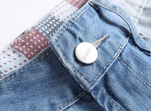 Détail de la taille d'un short en jean bleu clair avec bouton argenté et doublure carreaux