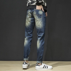 Macro view of slim fit distressed denim pants with V-stitch back pocket and heavy wash