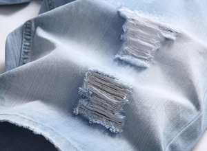 Makroaufnahme von hellblauen Jeans-Shorts mit Details zu destroyed Rissen und weißen Fäden