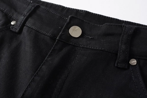 Gros plan d'un bouton en argent et de rivets sur un jean noir avec des coutures de qualité