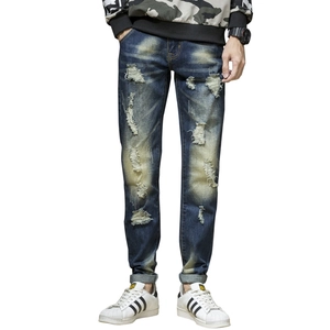 Detailed view of men's slim fit distressed blue jeans with vintage washed whiskers