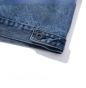 Macro view of blue denim jacket hem featuring high-quality stitching and metal button