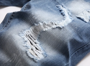 Detail of distressed blue denim shorts with heavy ripped white cotton thread fringing