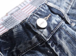 Detail of matte silver button with JEANS engraving and stitching on blue denim shorts