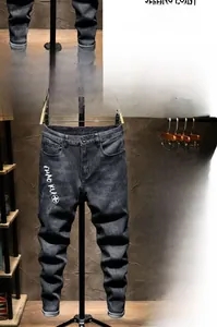 Detail of slim-fit black jeans with trendy letter print and washed denim fabric