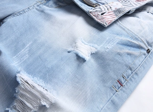 Nahaufnahme hellblauer Denim-Shorts mit Rissen und geprägtem Metallknopf im Detail