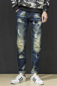 Detailed close-up of slim fit distressed denim jeans with ripped holes and washed finish
