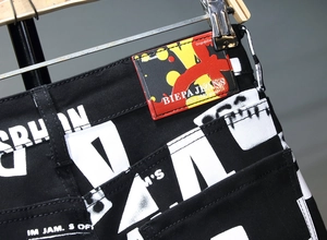 Detail von schwarzen Streetwear-Jeans mit weißen Buchstaben und BIEPA Leder-Backlabel