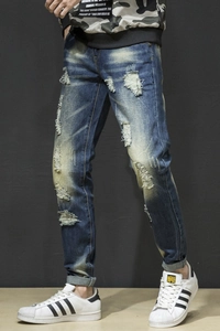 Close-up of distressed blue denim fabric with heavy washed effects and ripped fringe detail
