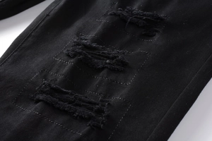 Détails rapprochés des déchirures et des bords effilochés sur un jean denim noir