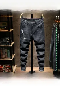 Close-up of slim-fit black denim jeans featuring white silk-screened graphics and wash effects
