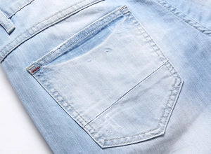 Nahaufnahme der Gesäßtasche hellblauer Denim-Shorts mit Kontrastnähten und Webstruktur