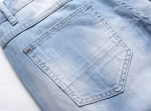 Macro detail of denim back pocket with light wash texture and red woven label accent
