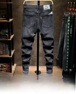 Detail of slim fit black denim jeans showing leather logo patch and red pocket tab