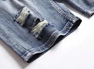Detailed macro view of distressed denim shorts showing ripped holes and frayed textures