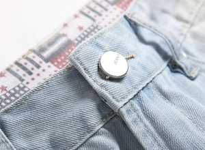 Détail macro d'un bouton argenté gravé JEANS et d'une doublure intérieure à motif étoilé
