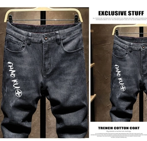 Detailed close-up of dark grey slim fit jeans featuring white text printing and distressed wash
