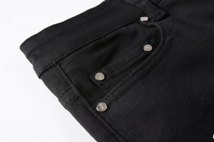 Gros plan sur la poche en denim noir avec rivets argentés gravés JEANS