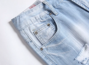 Detail von hellblauen Denim-Shorts mit Rissen, Metallnieten und verwaschenen Texturen